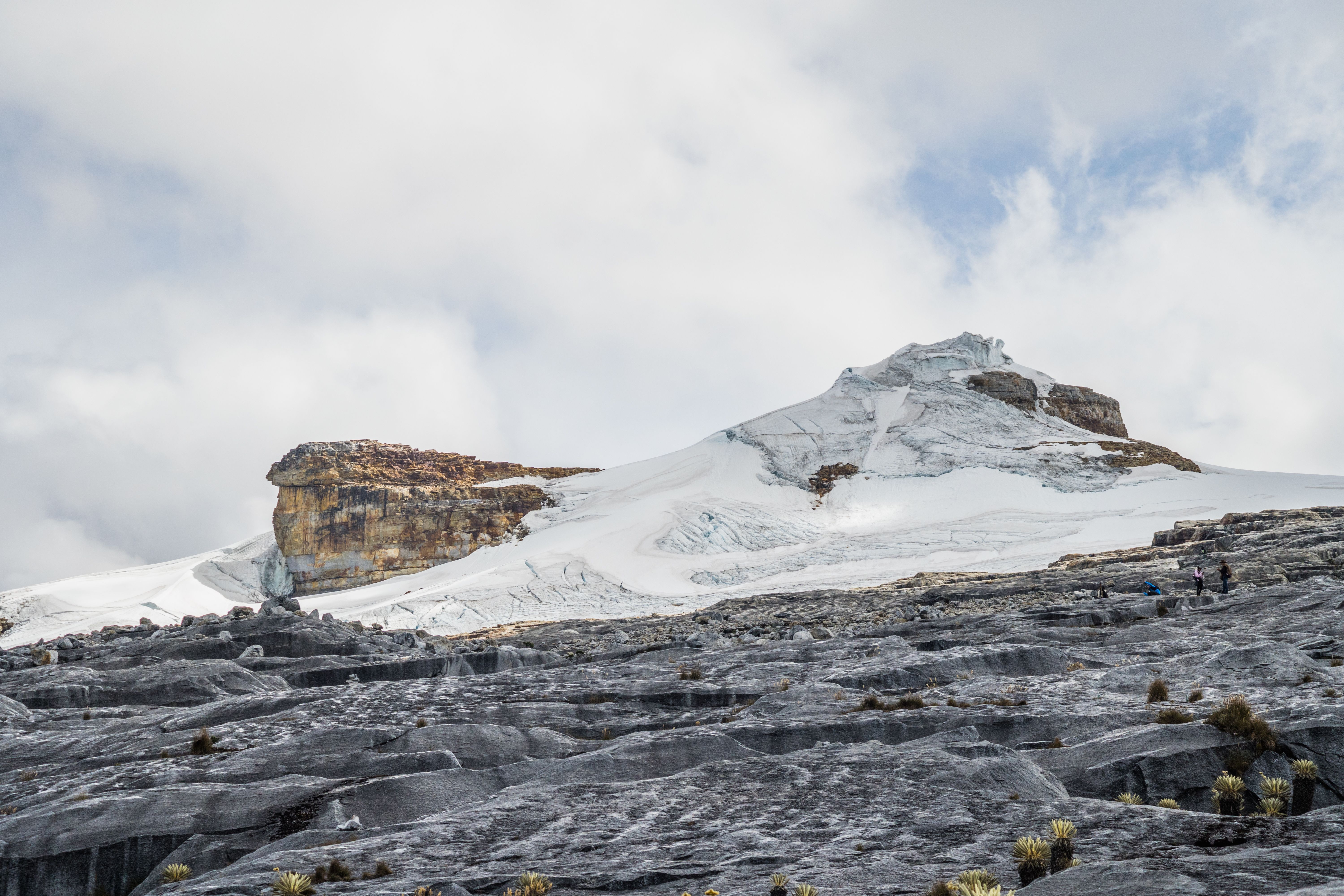 Hikers standing on rock near the edge of a glacier in Parque Nacional Natural El Cocuy, Colombia